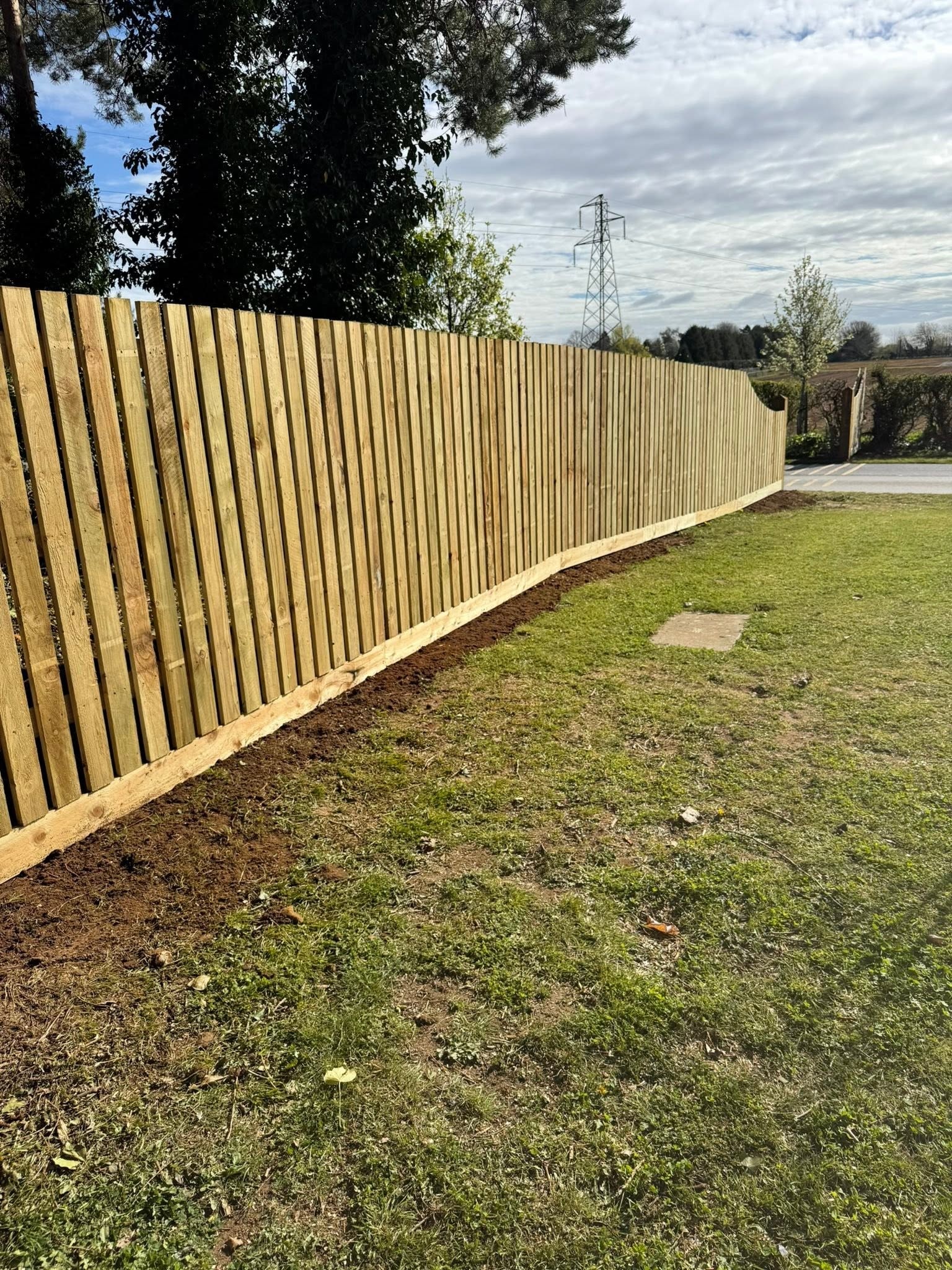 A long close-board fence along the edge of a field