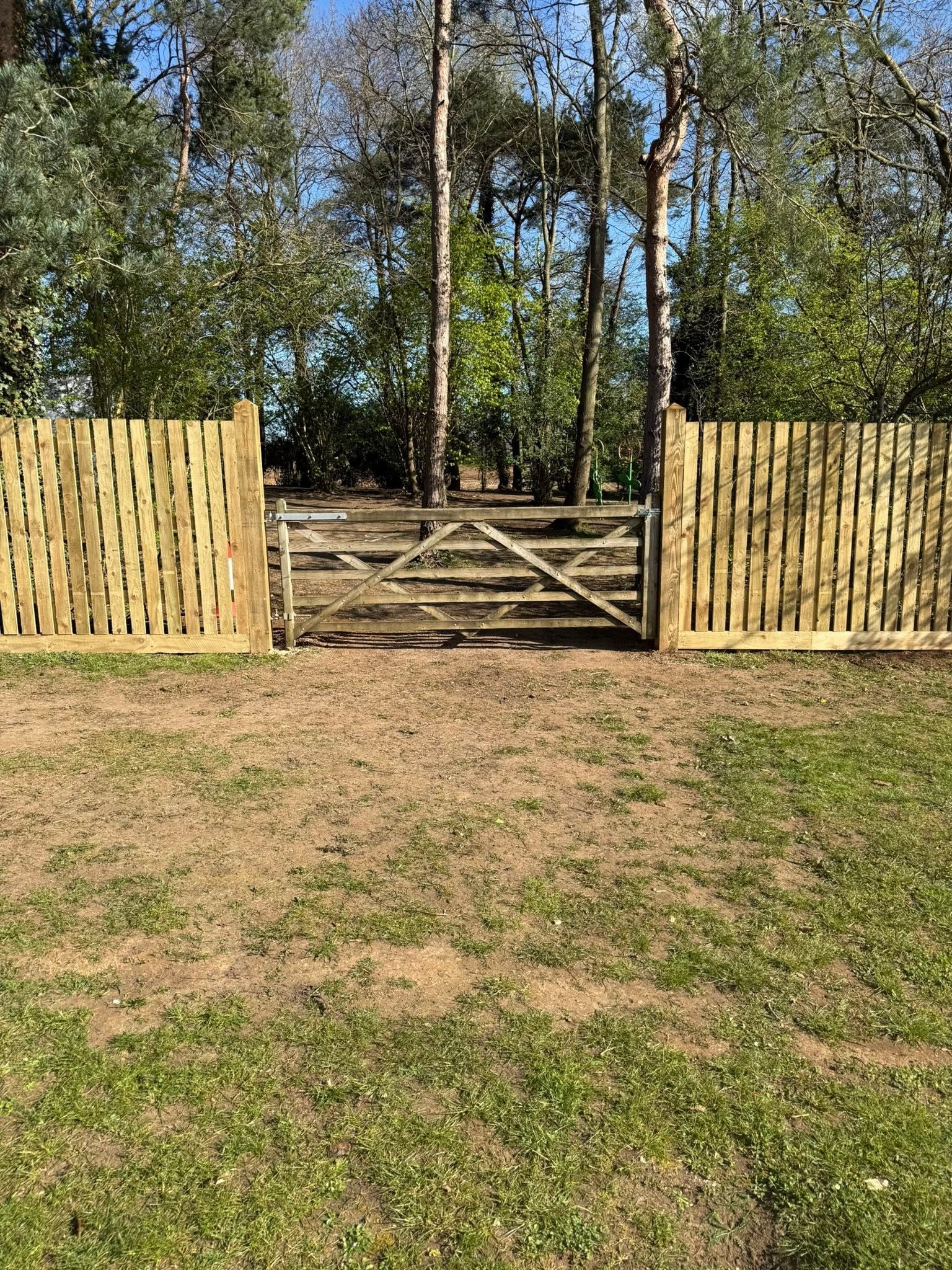 A timber five-bar field gate set into new close-board fencing