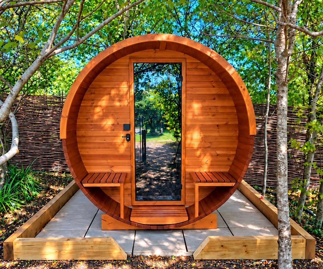A barrel sauna on a sandstone base with timber edging, among trees