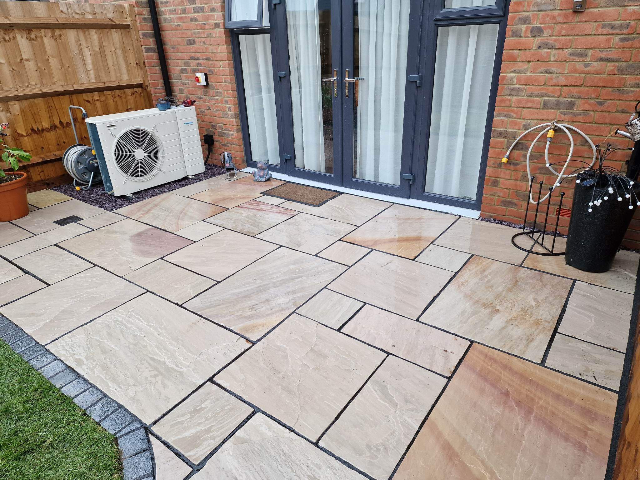 A new sandstone patio with grey block edging outside French doors