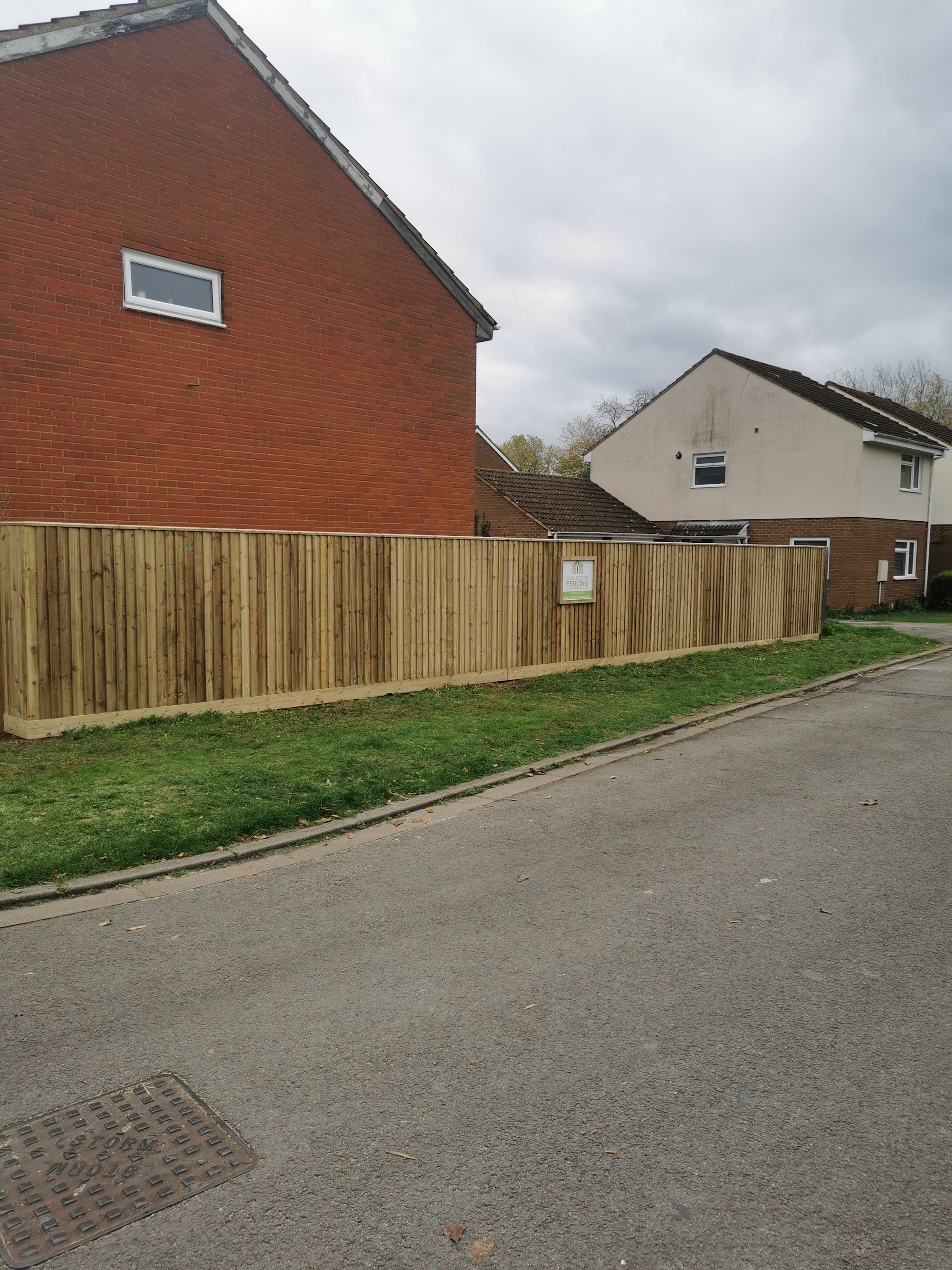 A long new close-board fence along a roadside verge