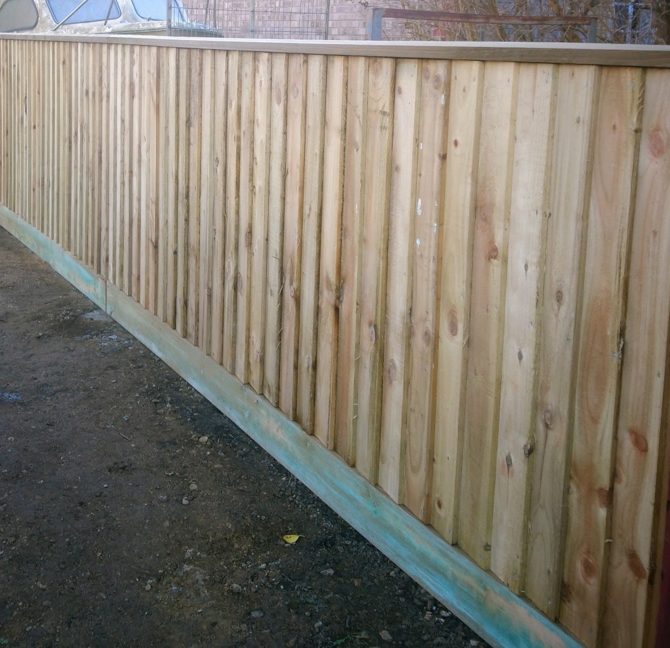 A long close-board fence with gravel boards on a cleared site