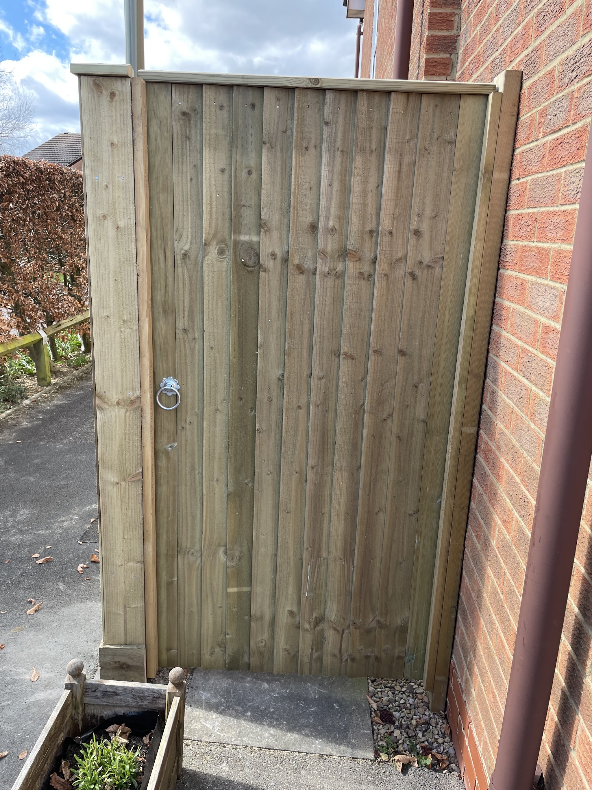 A tall close-board side gate between brick walls
